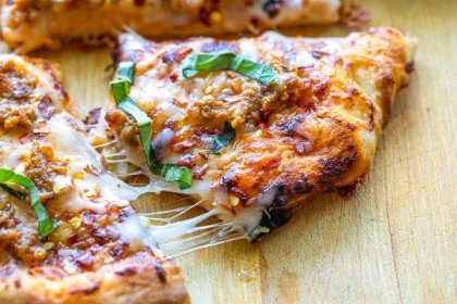 Klobásová pizza, vařená ve venkovní pizze Roccbox, trouba s vláknitým sýrovým plátkem, který ji spojuje se zbytkem pizzy