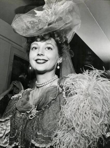 an old photo of a woman wearing a veil and dress with feathers on her head
