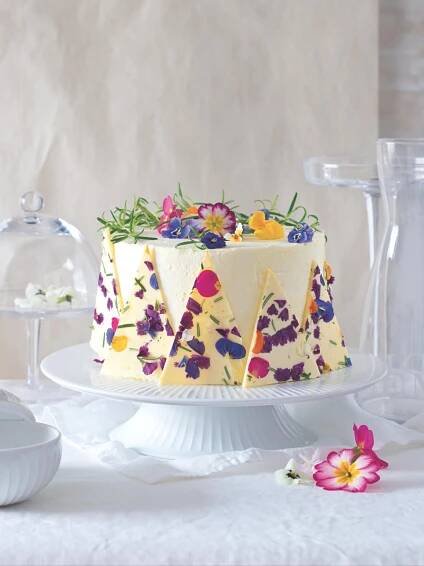 a cake with flowers on it sitting on top of a table next to plates and vases
