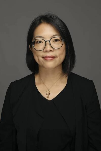 Porträt-Foto im Hochkant-Format: Gwen Hsin-Yi Chang hat schwarze Haare, trägt eine Brille, eine Kette und ein schwarzes Oberteil; sie lächelt in die Kamera (opens enlarged image)