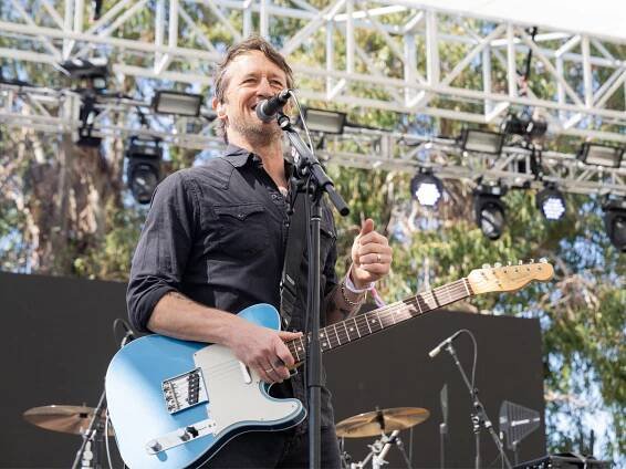 Chris Shiflett on stage with a Telecaster in hand. He is smiling and singing into a mic.
