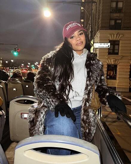 Woman wearing a fur coat on a bus in New York City.