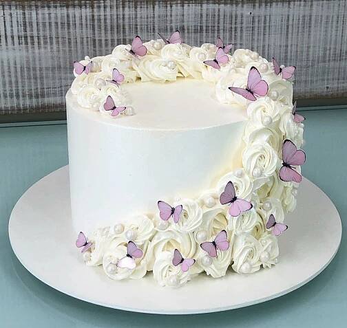 a white cake with purple butterflies on it