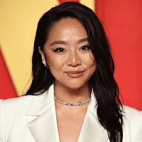 Stephanie Hsu with a deep parted wavy hairstyle, tucked behind her ear.