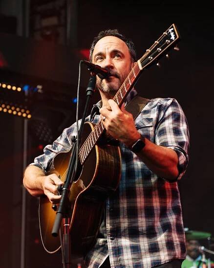 dave matthews holding a guitar, performing onstage singing into a microphone