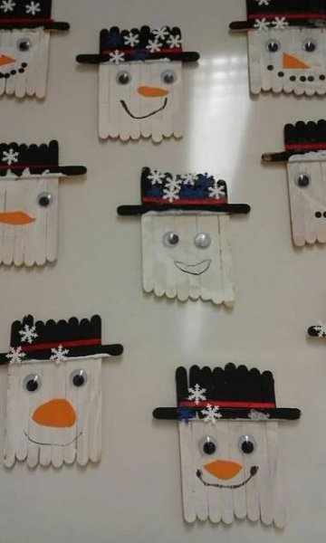 snowmen made out of construction paper on a white table with black and orange pins