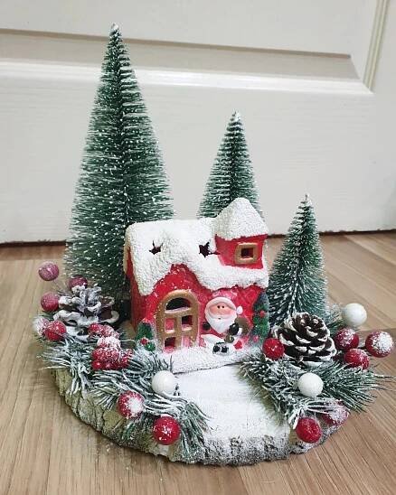 a christmas scene with a small house and pine trees on the floor in front of a door