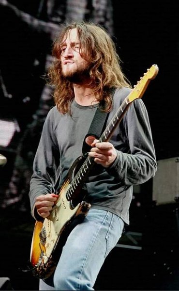 a man with long hair playing an electric guitar
