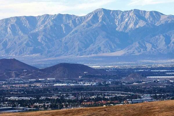 A hiker heads down a trail in Sycamore Canyon Wilderness Park on a clear day with Riverside and Mount Baldy peak in the background on a warm afternoon as high winds and Red flag warnings are expected in Riverside on Monday, November 22, 2021.