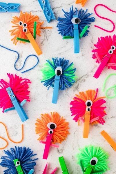 colorful paper pom poms with scissors and eyeballs in them on a white surface