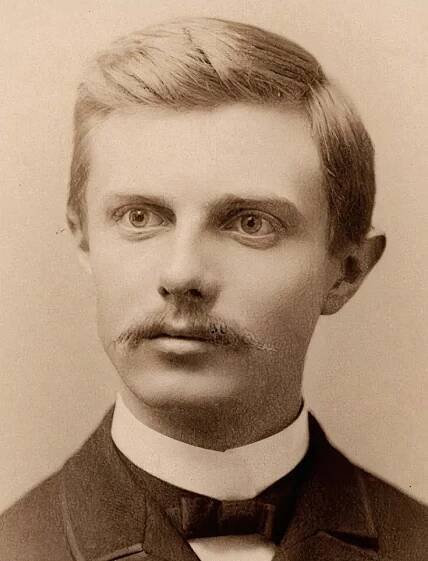 a head and shoulders portrait of a man with parted hair and a mustache wearing a bowtie