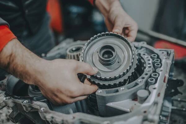 Mechanik drží v ruce součástku z motoru