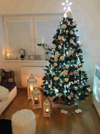 a decorated christmas tree in a living room with candles and other decorations on the floor
