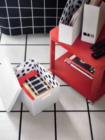 A white TJENA storage box and magazine files with an interior spot print placed on, and next to, a red side table on wheels.