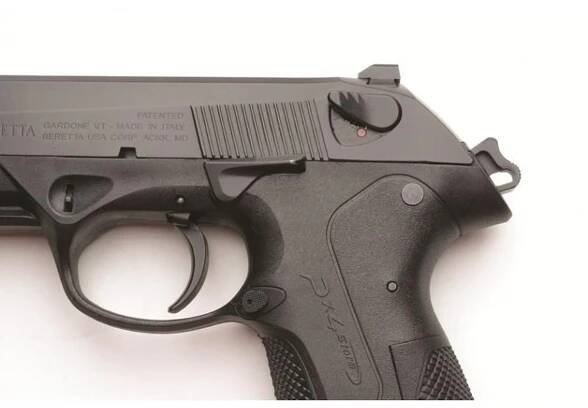 Detailný pohľad na pištoľ Beretta PX4 Storm, zobrazuje časť rámu, spúšť a bezpečnostné prvky. Pištoľ je čiernej farby s ergonomicky tvarovaným držadlom.