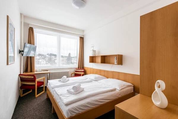 a hotel room with a bed and a desk and a window at HOTEL AGRI in Soběšice