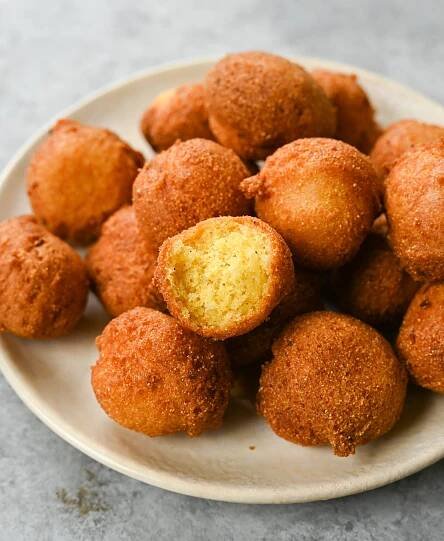 Pile of hush puppies, one of which is missing a bite.