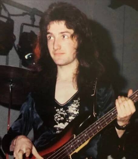 a man with long hair holding a guitar