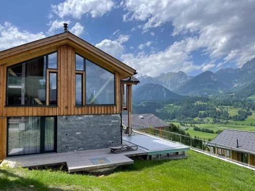 a house on a hill with a view of mountains at Bergresort Hauser Kaibling by ALPS RESORTS in Haus im Ennstal