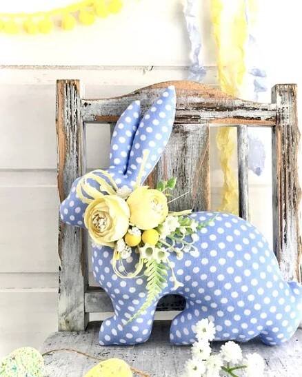 a blue and white polka dot bunny sitting on top of a wooden chair next to flowers