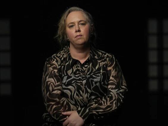 Woman sits and looks at the camera with black background