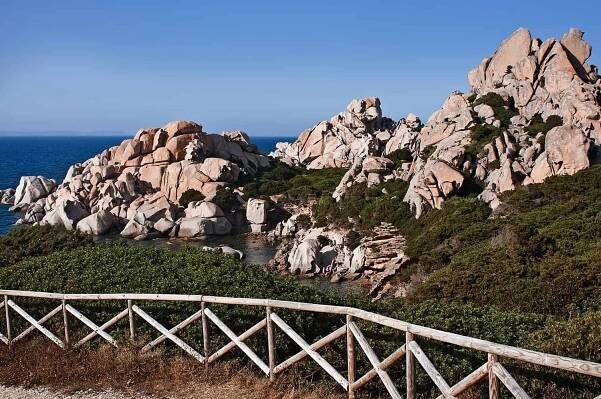 renting a car in olbia sardinia gives you freedom to visit stunning remote beaches- capo testa with is impressive boulder and blue sea
