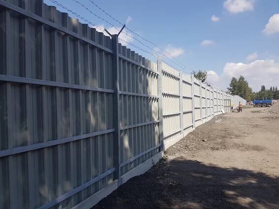 Trapézový plech výšky 300 cm + podhrabová deska. Zakončení ostnatým drátem.