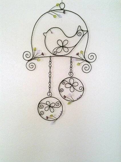 a metal wall hanging with two birds on it's sides and flowers in the middle
