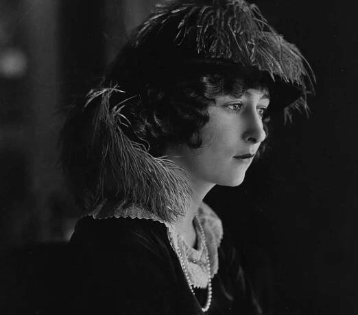Mildred Harris wearing a hat and black dress 