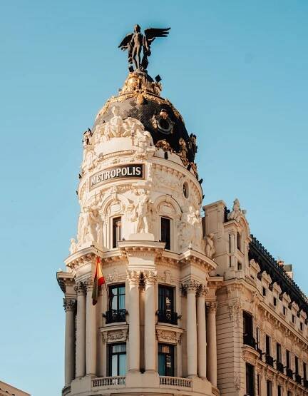 Ornate Beaux-Arts architectural dome with Metropolis text and winged statue against blue sky.