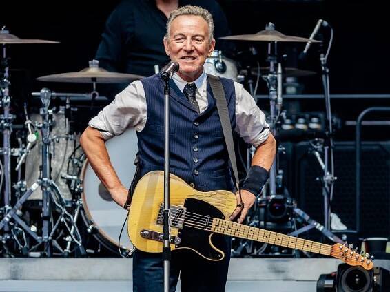 Bruce Springsteen pointing to the crowd and holding his guitar with the other hand
