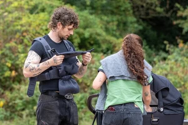Tom Grennan and his wife with their baby in a park.