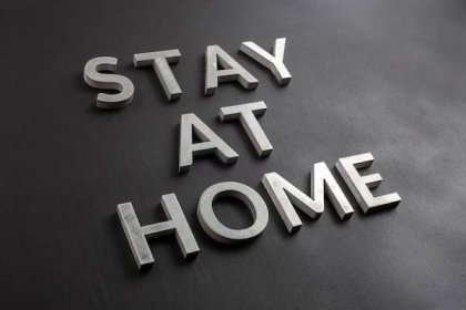 The words stay at home laid with brushed aluminium letters on matte black background in diagonal