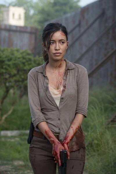 Christian Serratos as Rosita Espinosa in The Walking Dead, covered in blood and holding a gun.