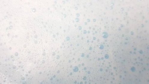 Bílá pěna s bublinkami praskajícími v modré vodě — Stock záběr