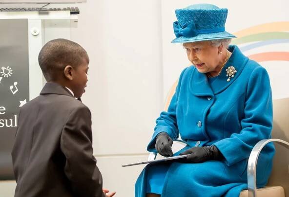 Queen Elizabeth II is presented with a tablet computer by John Samson, 12, during her visit to the Royal Commonwealth Society on November 14, 2012