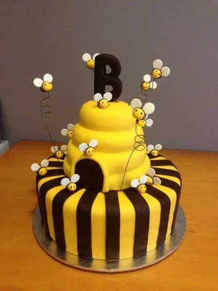 a yellow and black striped cake with bees on top
