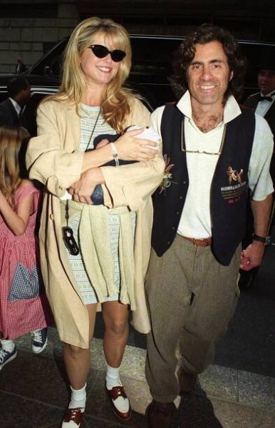 Christie Brinkley in a beige duster and grey dress with white socks and brown loafers, wearing sunglasses., carrying son Jack Brinkley Cook. Randy Taubam in a waistcoat, white T-shirt and khaki pants.
