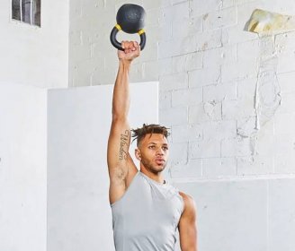 Black athlete demonstrating bottoms-up press with kettlebll in gym