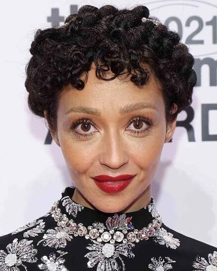 Ruth Negga wears curly pixie cut and red lipstick with a black, diamond-embellished dress