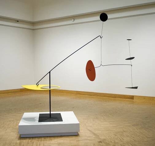 a stabile with yellow, red, and black discs balanced on wires
