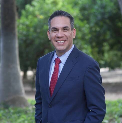A man in a suit and tie is smiling for the camera.