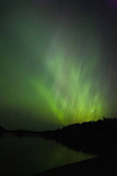 Bright green northern lights over French lake in quetico.