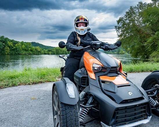 Rider on Can-Am Ryker 900 Rally Edition with lake behind her.