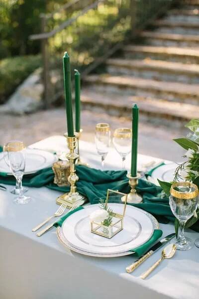 the table is set with green napkins and gold place settings, along with candles