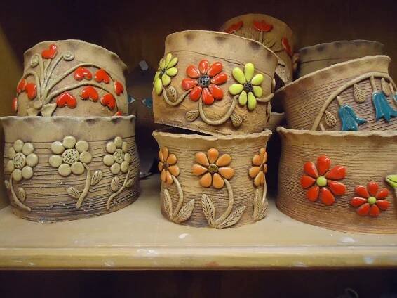 several baskets with flowers and birds on them are sitting on a shelf in a store