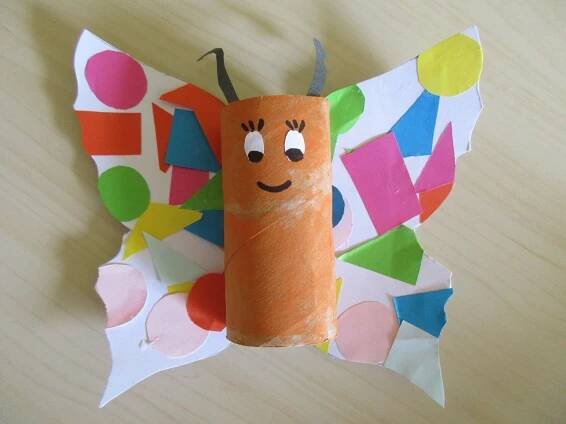 a butterfly made out of toilet paper on top of a wooden table with circles and shapes around it