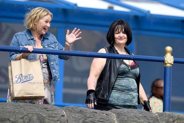 two women standing next to each other with a boots bag