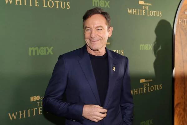 Jason Isaacs smiling on the red carpet of a 'White Lotus' event