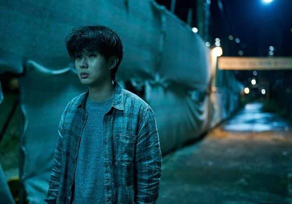 A young man walks in a dark alley.